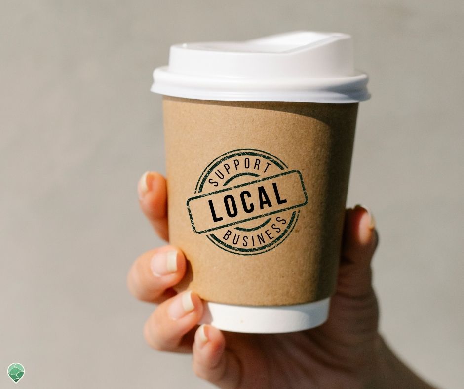 Disposable coffee cup with a stamp on it that says "Support Local Business"