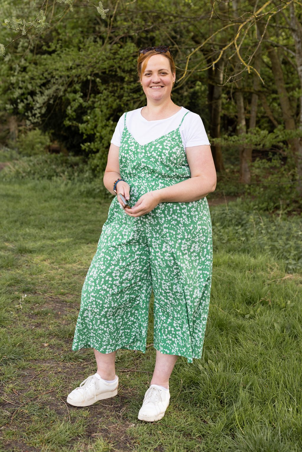 Corinne standing holding her phone and smiling at the camera