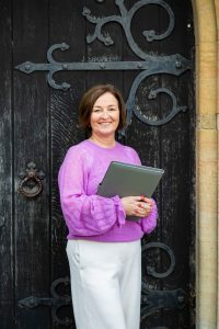Jeanette from JK Celebrant standing holding a folder and smiling at the camera